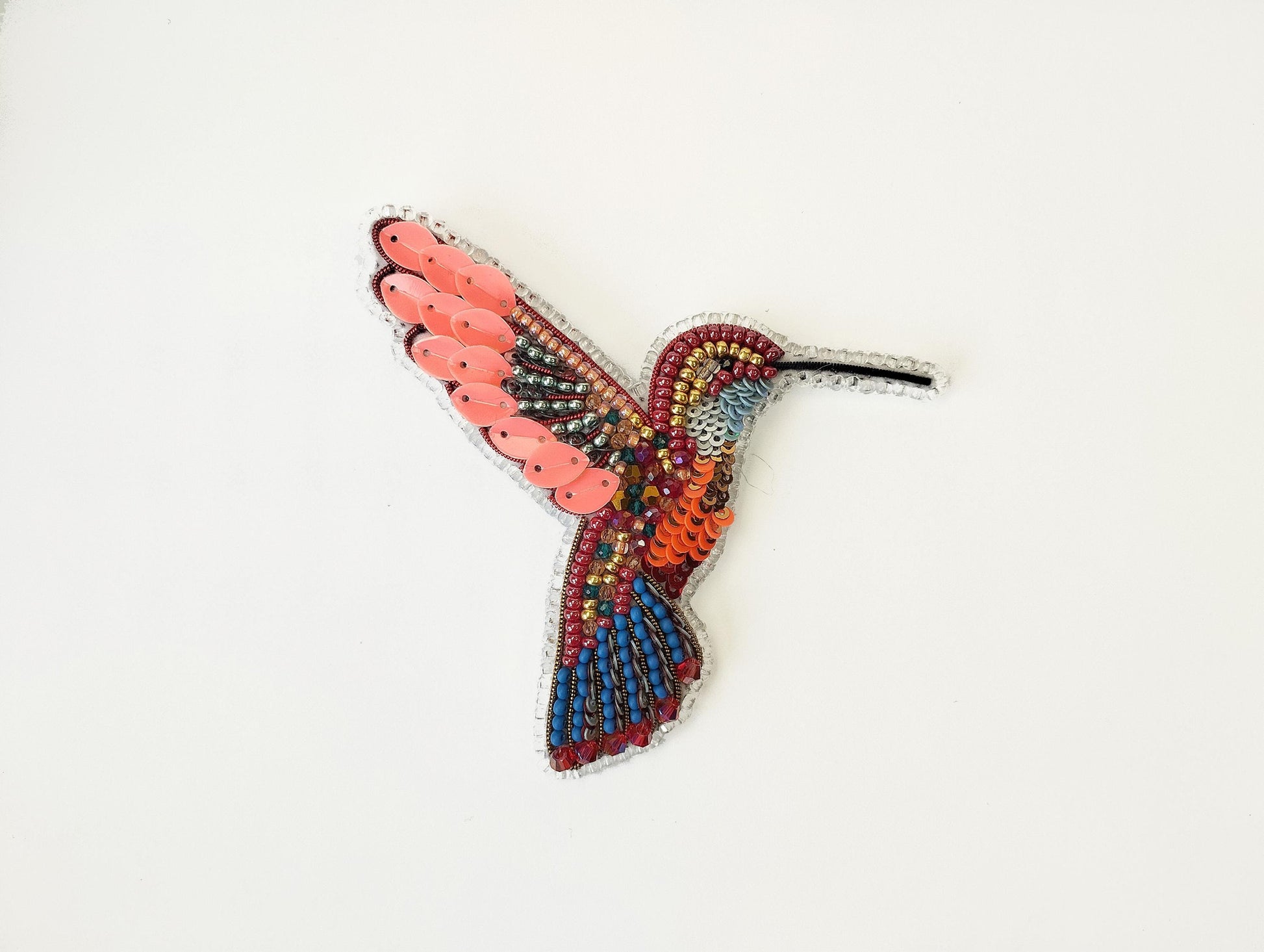 a colorful bird made out of beads on a white surface