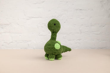 a crocheted green dinosaur sitting on a table