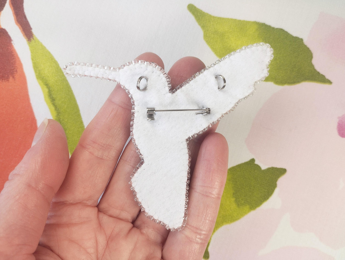 a person holding a piece of fabric with a pin in it