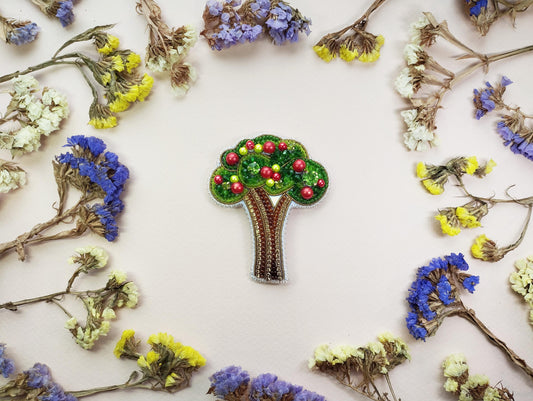a brooch with a tree on it surrounded by flowers