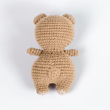 a crocheted teddy bear sitting on a white surface