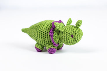 a green crocheted toy with a purple ribbon around its neck