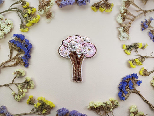 a brooch with a tree on it surrounded by flowers