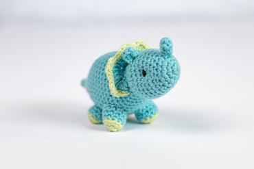 a small blue crocheted elephant sitting on a white surface