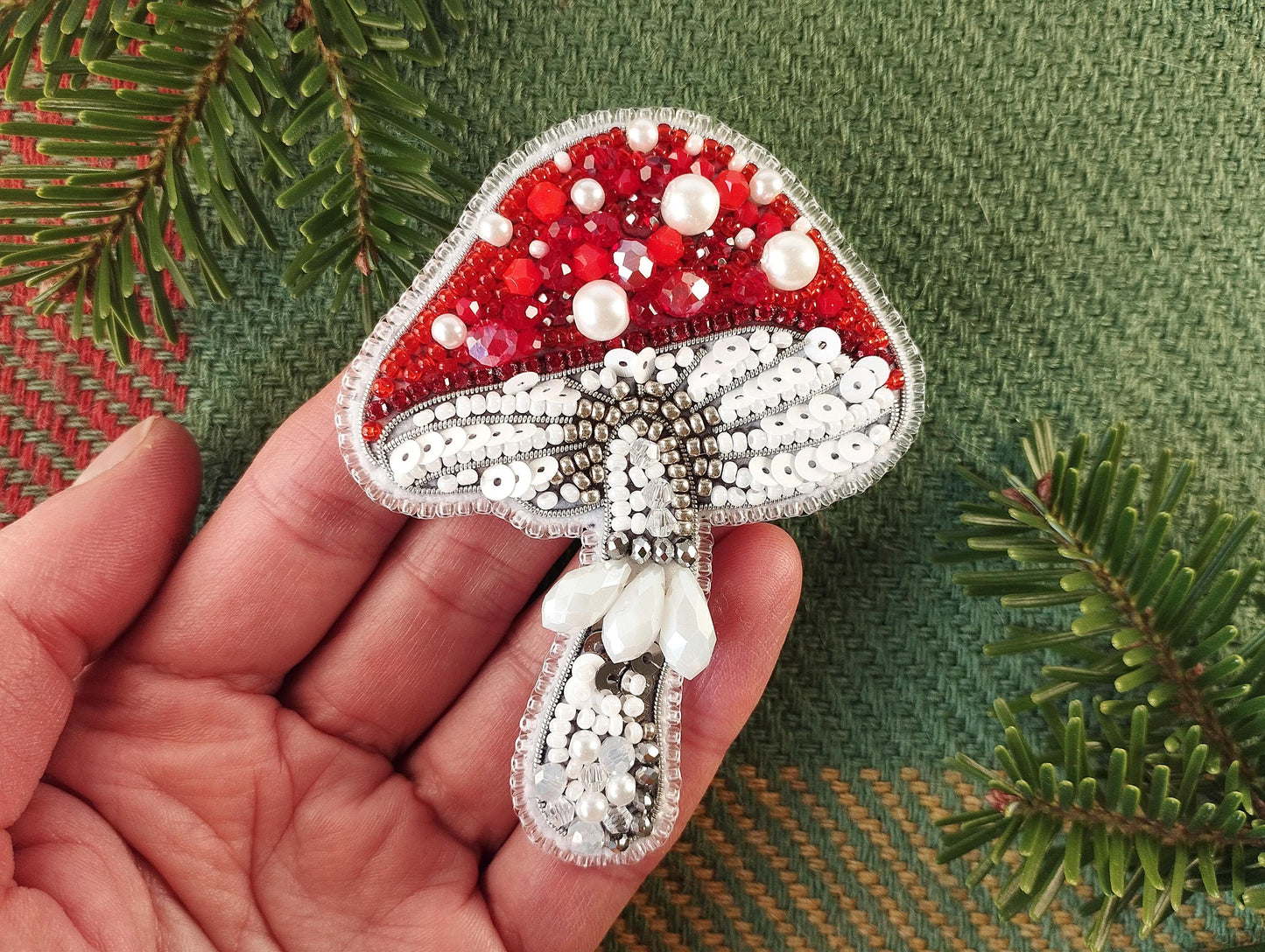 a hand holding a red and white brooch