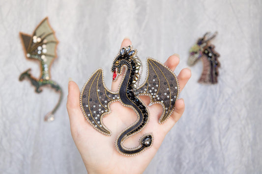 a hand holding a dragon figurine next to other dragon figurines
