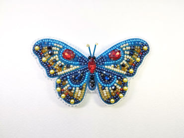 a beaded butterfly with red eyes on a white background