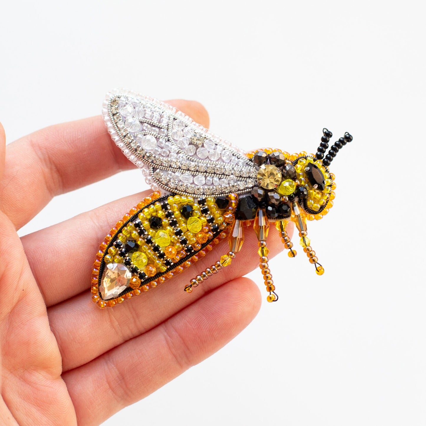 a hand holding a beaded insect in it's left hand