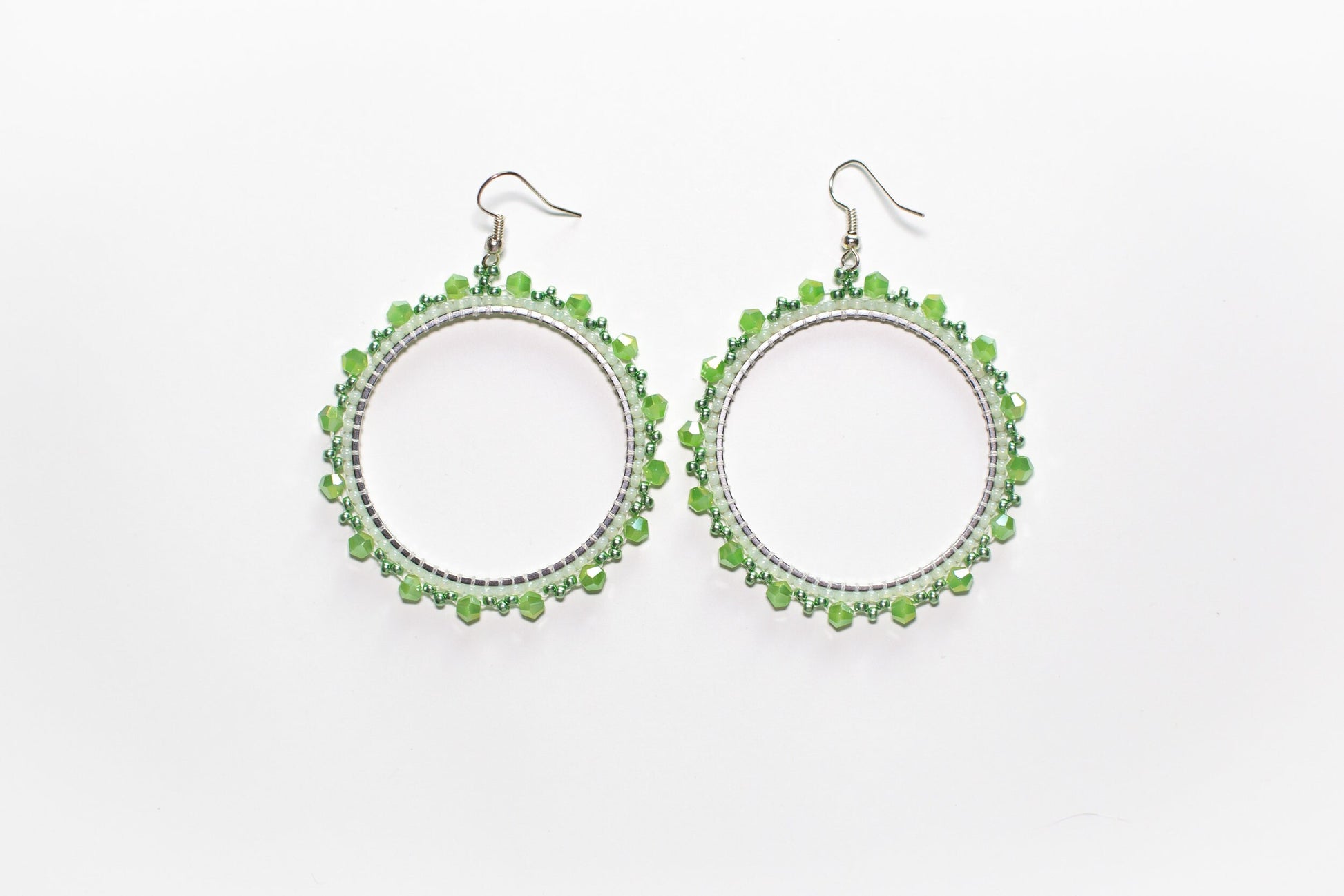 a pair of green beaded earrings on a white background