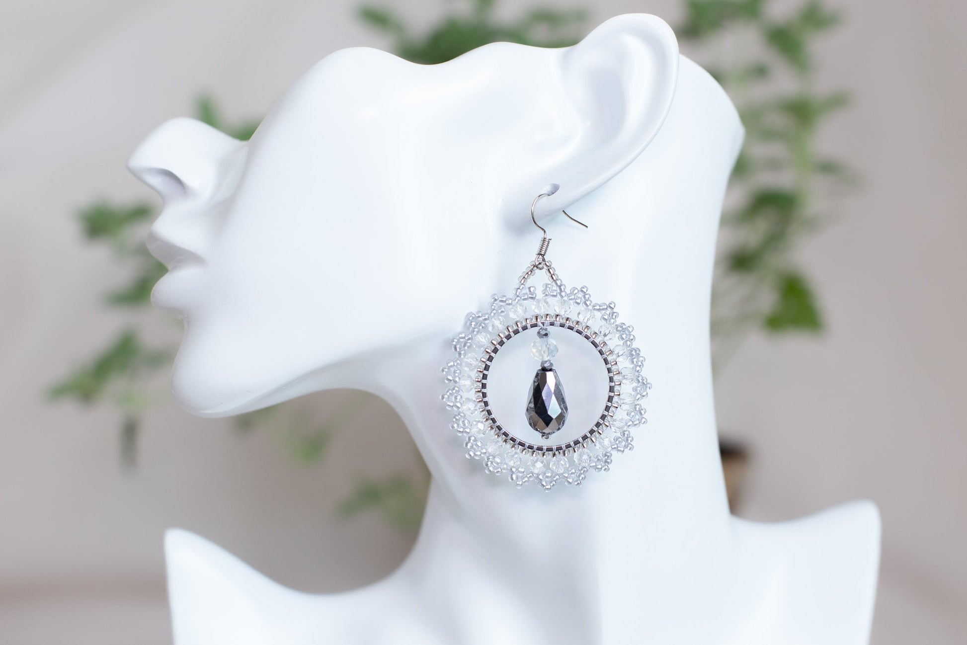 a white mannequin head with a pair of earrings on it