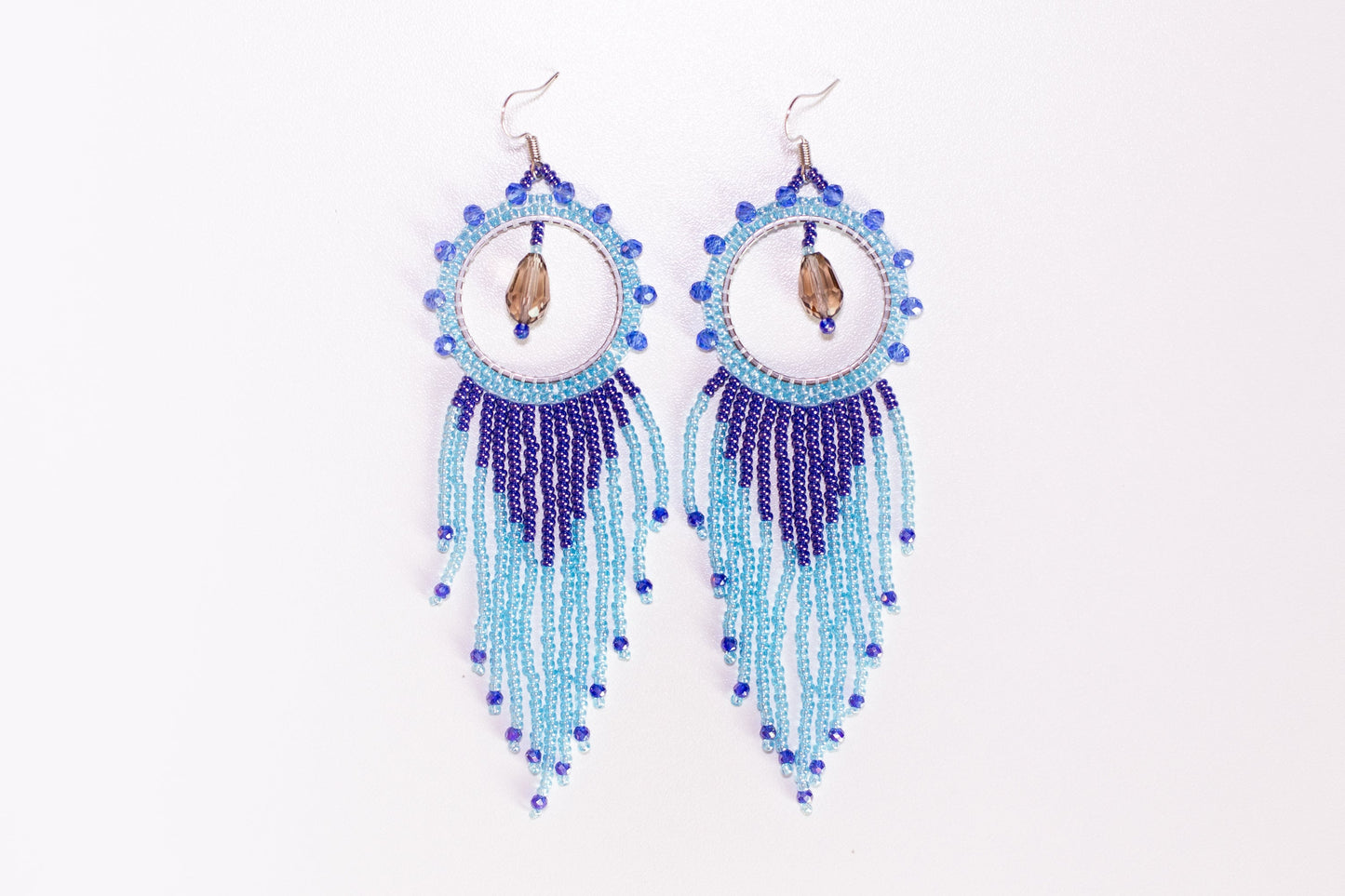 a hand holding a pair of blue beaded earrings