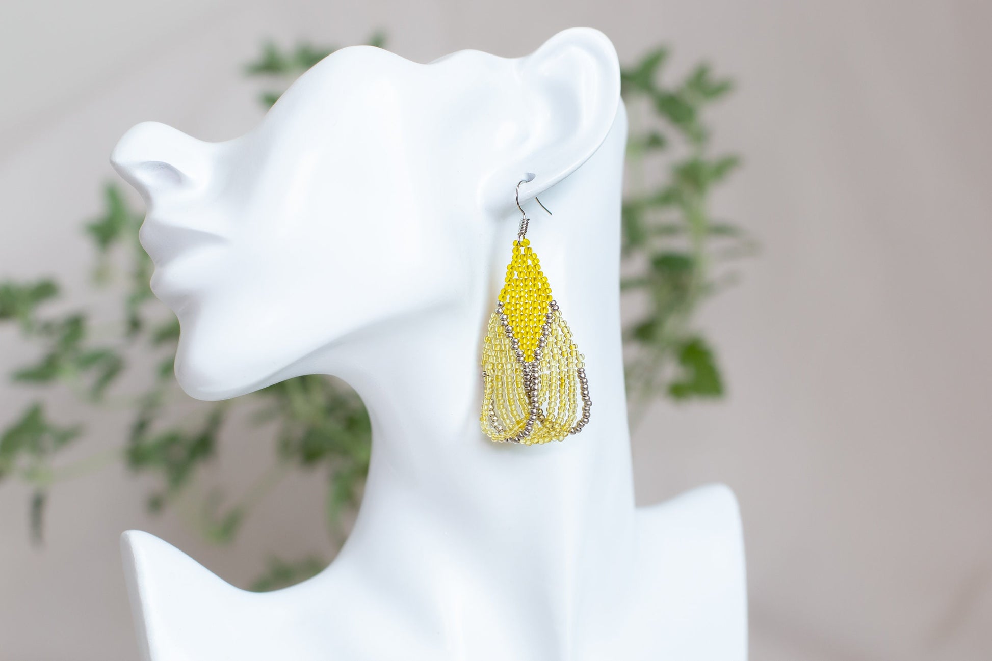 a white mannequin head with a pair of earrings on it