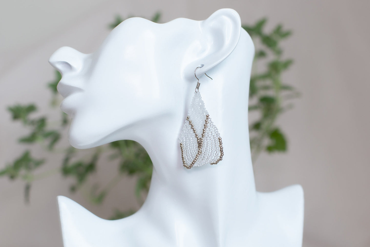 a white mannequin head with a pair of earrings on it