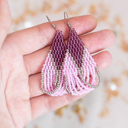 a pair of pink beaded earrings on a pink background