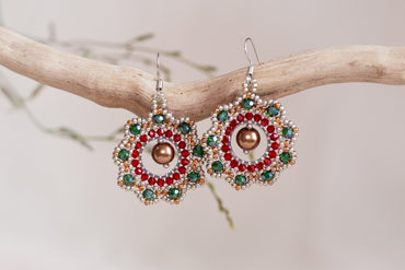a pair of red, green, and gold earrings on a branch