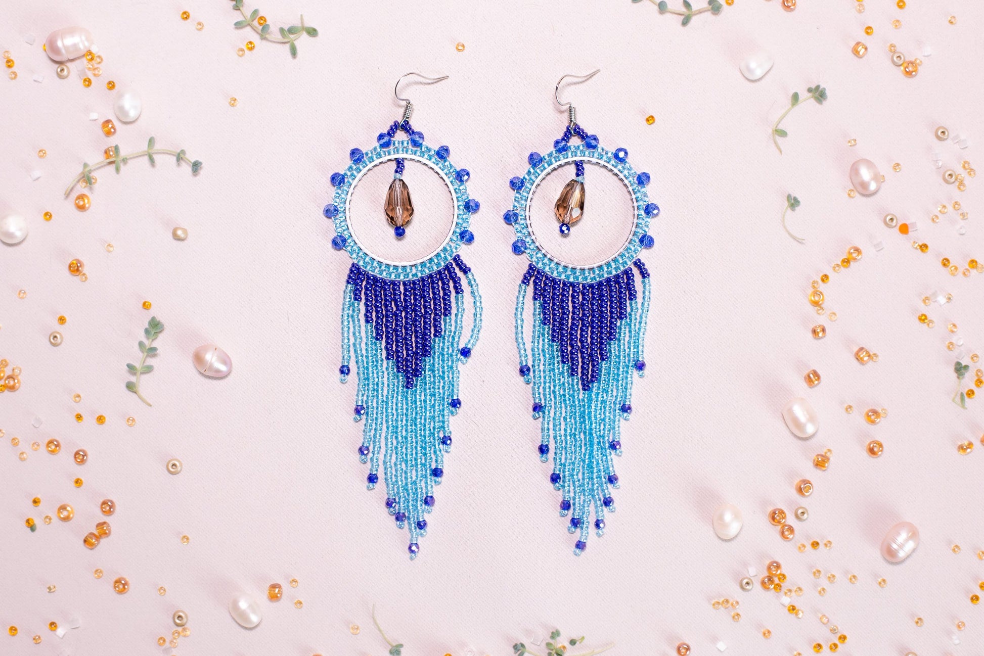 a pair of blue beaded earrings sitting on top of a table