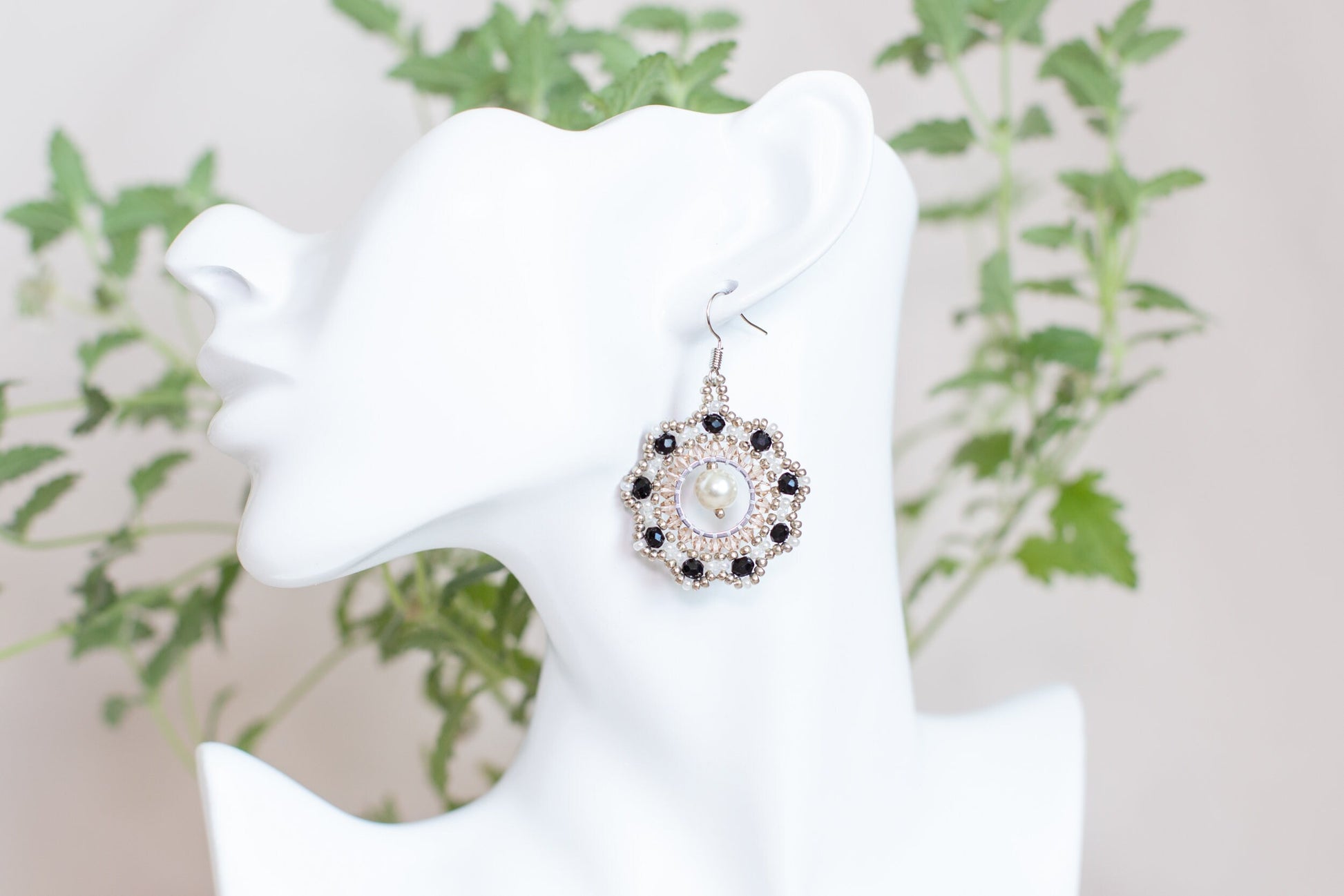 a white mannequin head with a pair of earrings on it