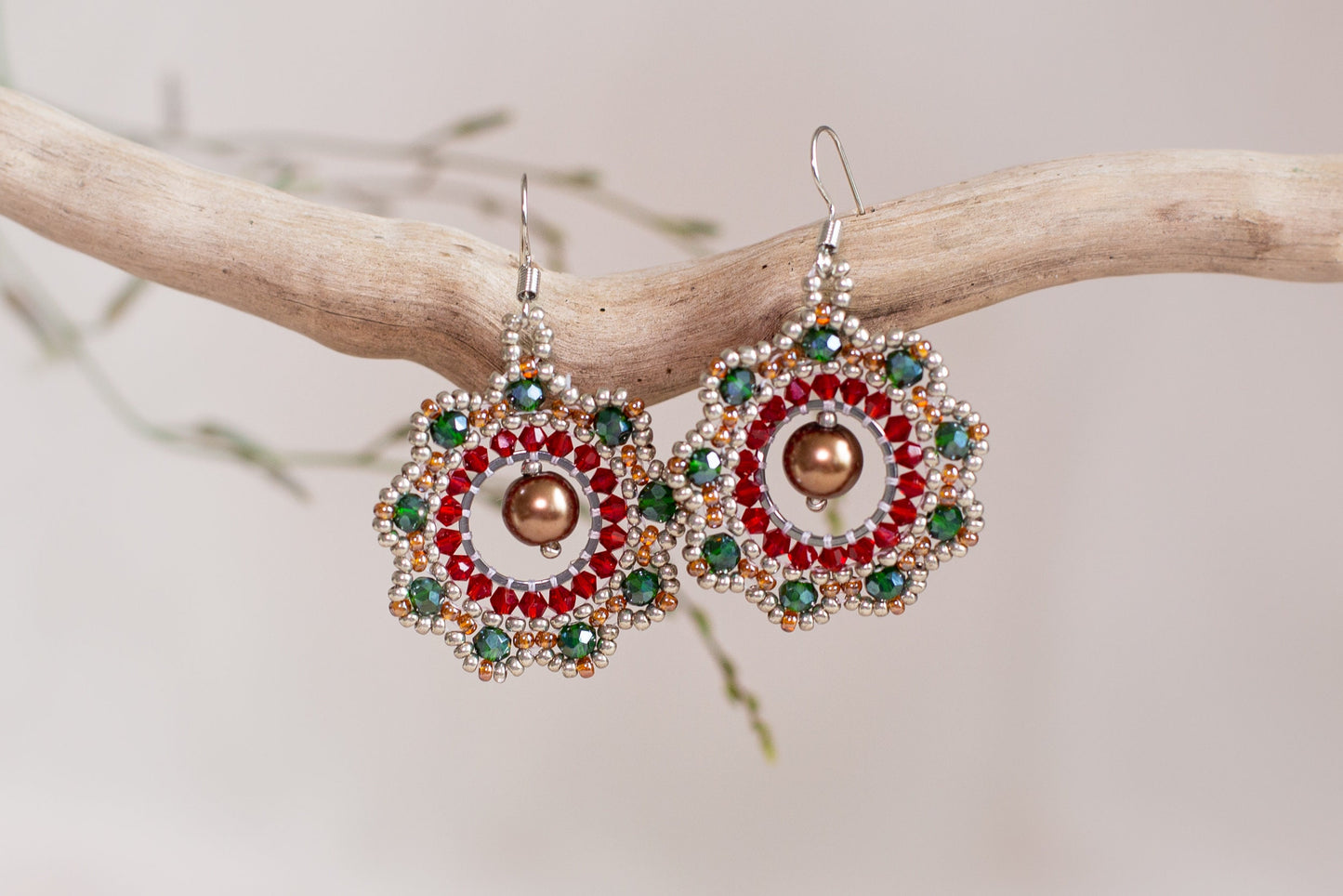 a pair of red, green, and gold earrings on a branch