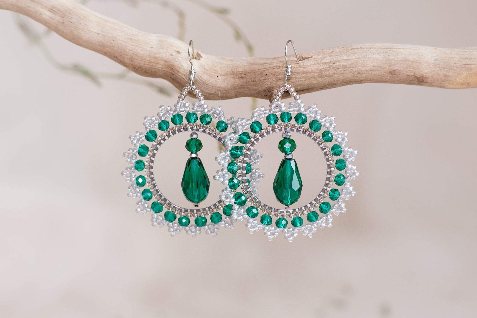a pair of green and white earrings hanging from a tree branch