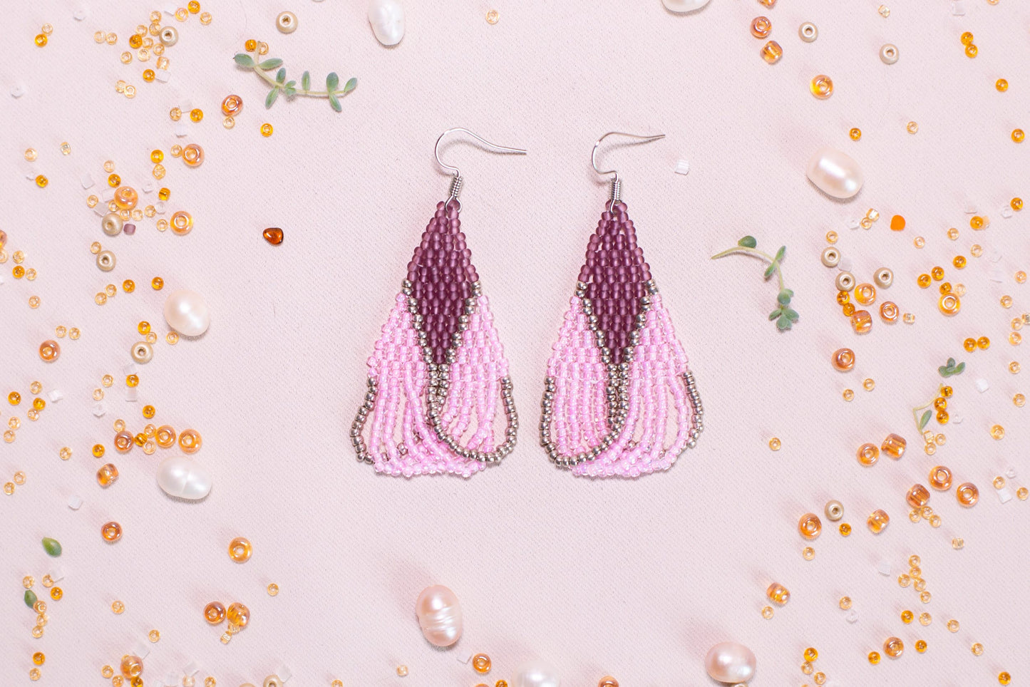 a pair of pink beaded earrings on a pink background