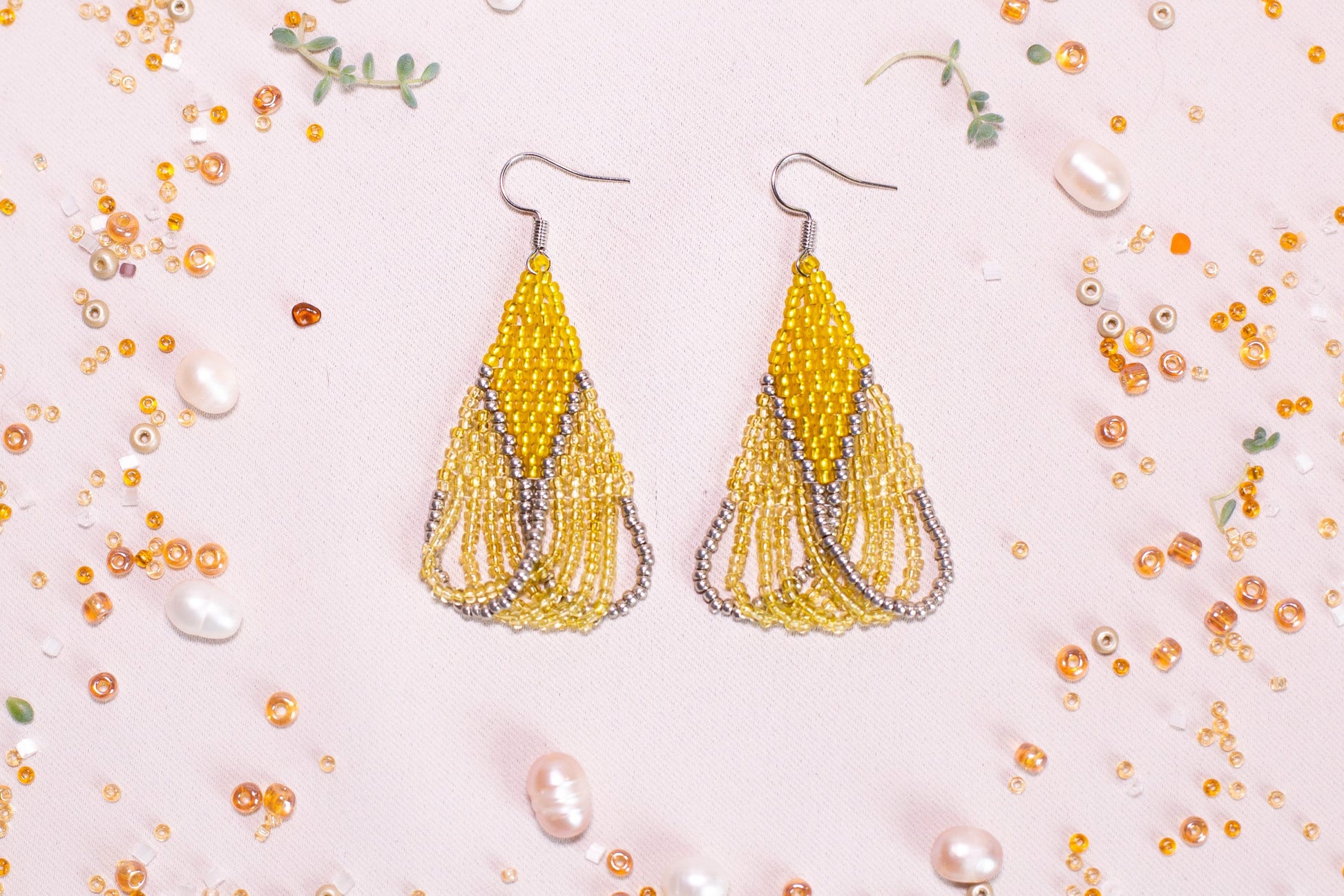a pair of yellow beaded earrings sitting on top of a table