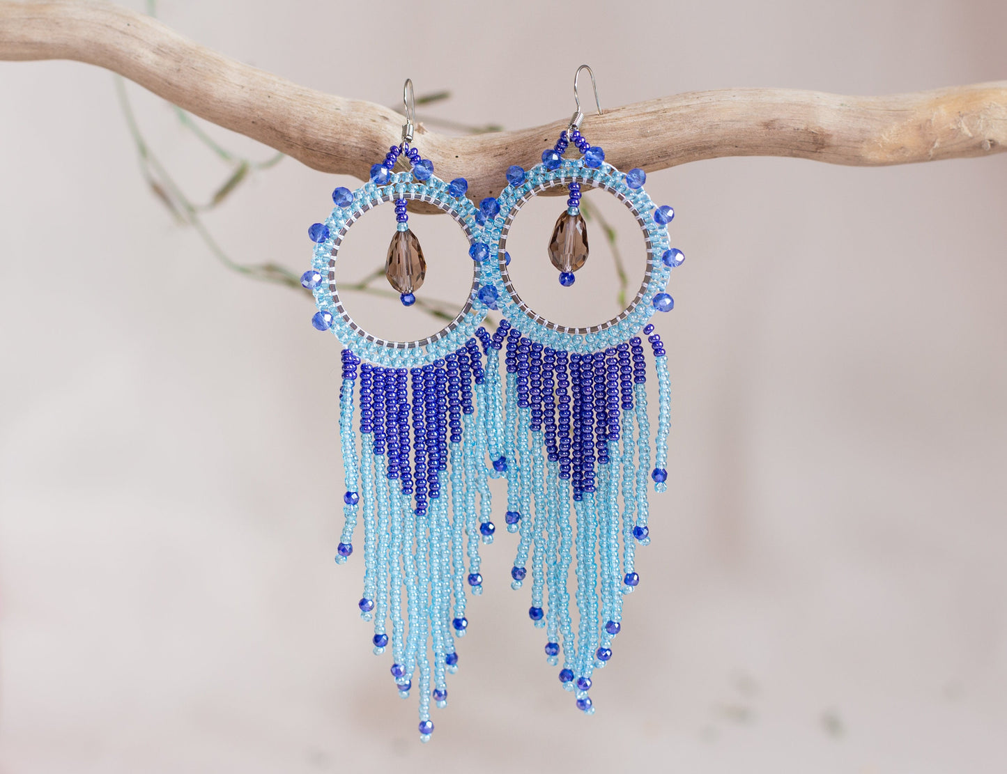 a pair of blue beaded earrings hanging from a tree branch
