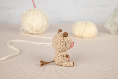 a small crocheted mouse sitting next to two balls of yarn