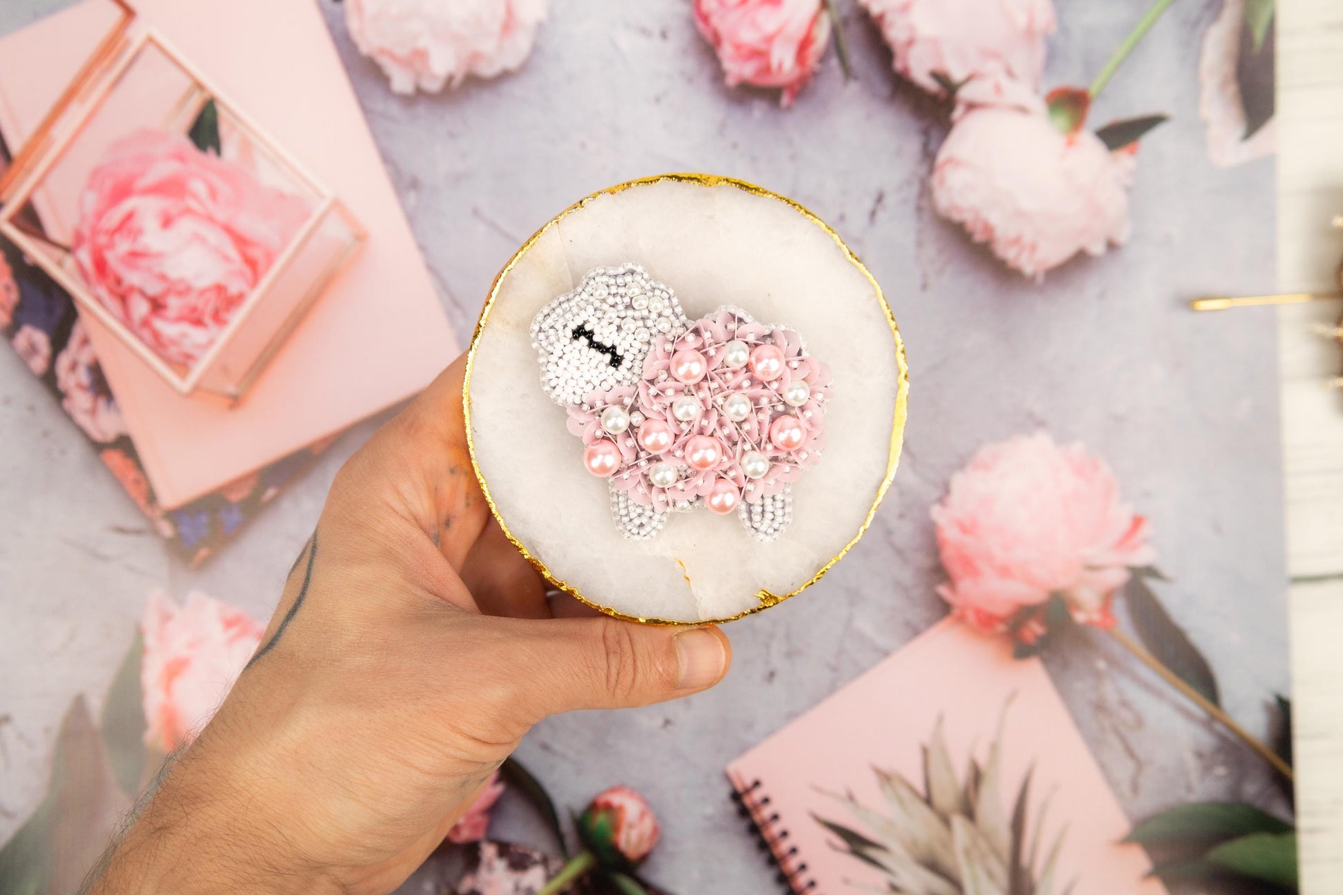 a person holding a cupcake decorated with pink and white sprinkles