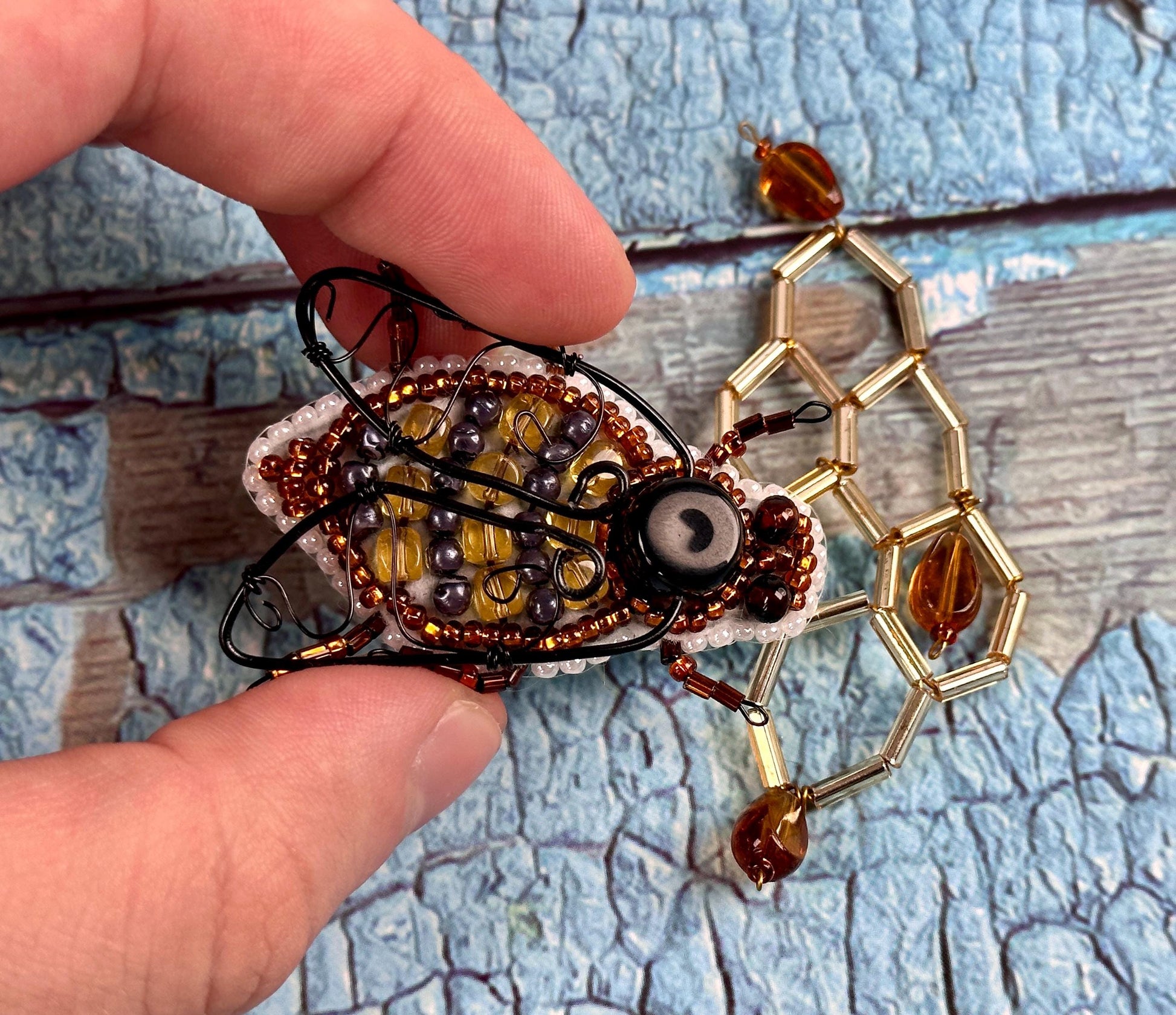 a person holding a piece of art made of beads