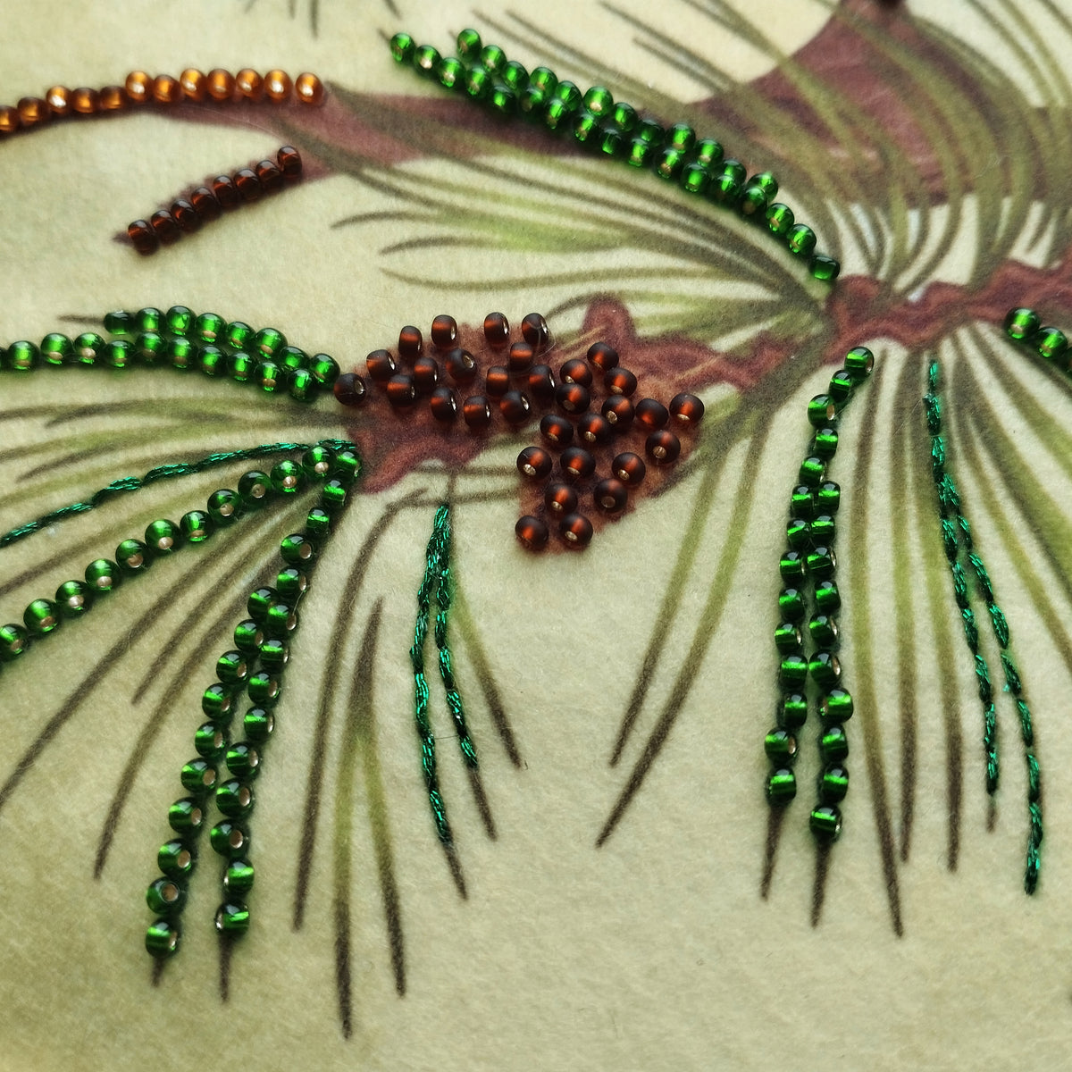 a close-up view of a pine branch with green and red beads, as well as some brown beads, arranged in a decorative manner.