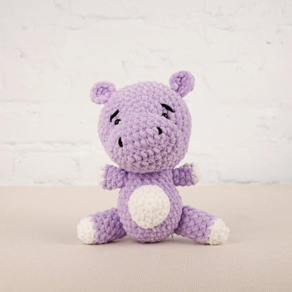 a purple crocheted stuffed animal sitting on a table