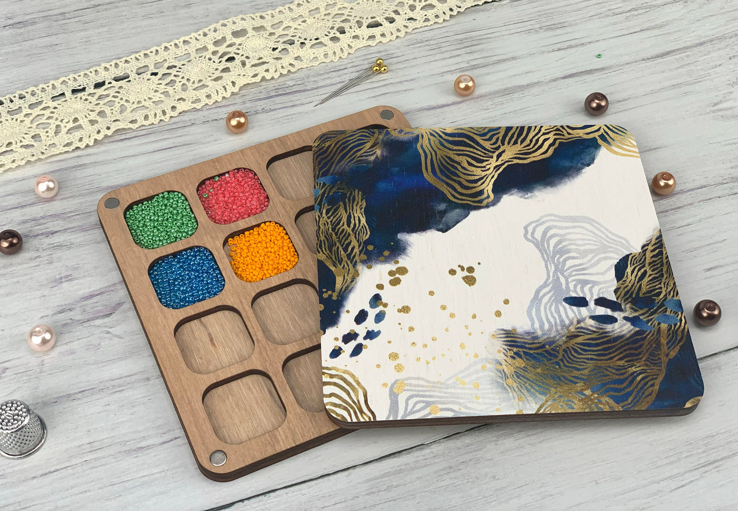 a wooden tray with a paint palette and some beads