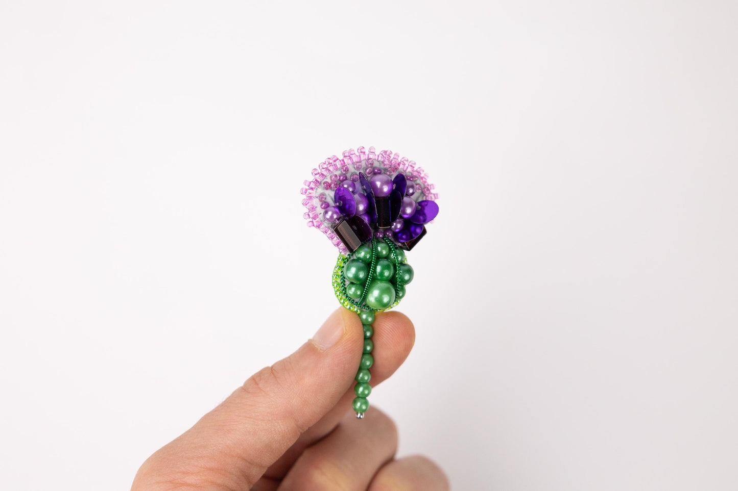 a person is holding a flower made out of beads