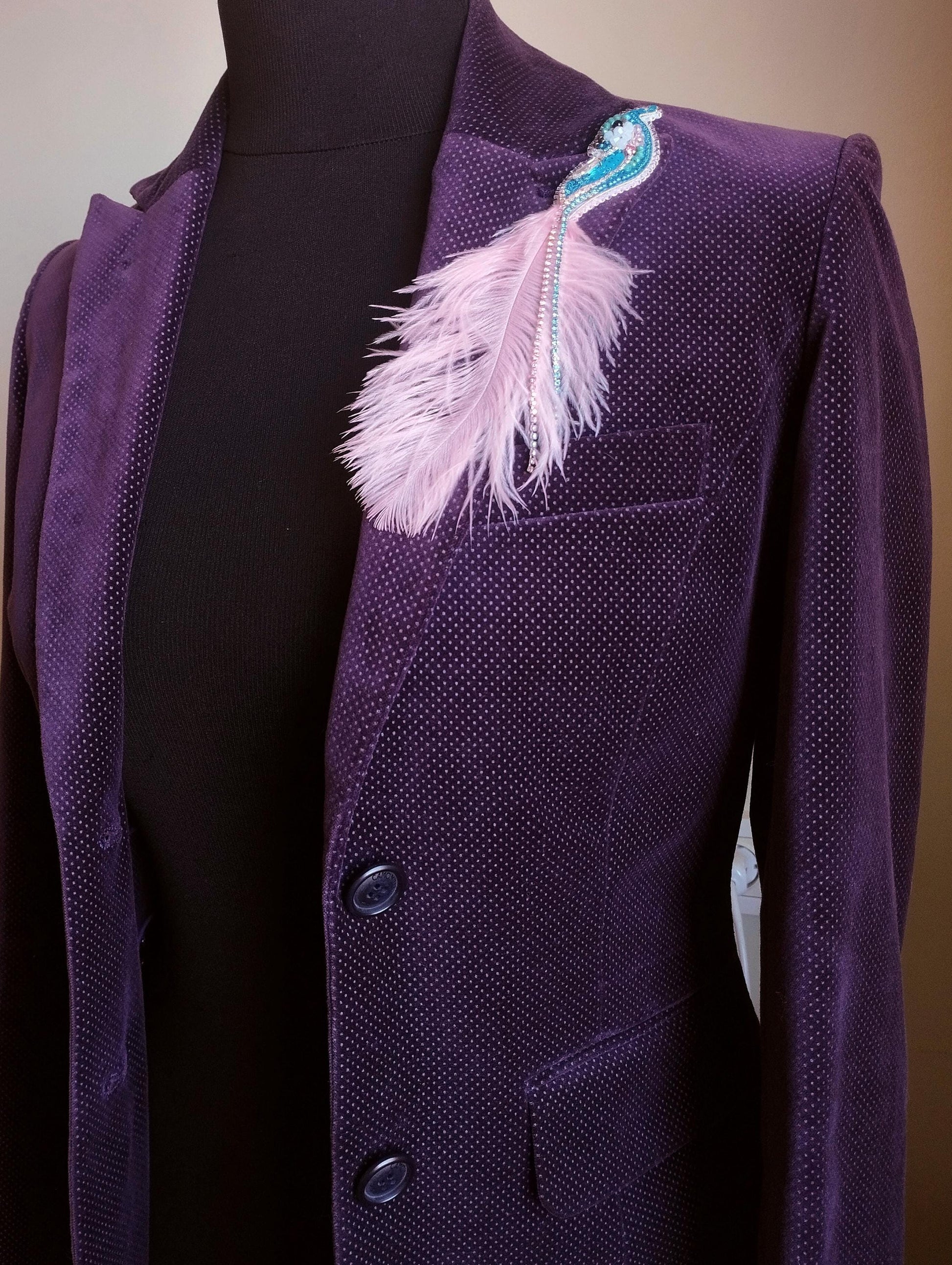 A purple velvet jacket with a feather pin on the left side.
