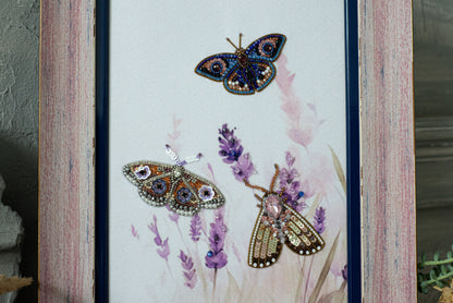 three butterflies with intricate beading and embroidery designs, set against a background of purple flowers.