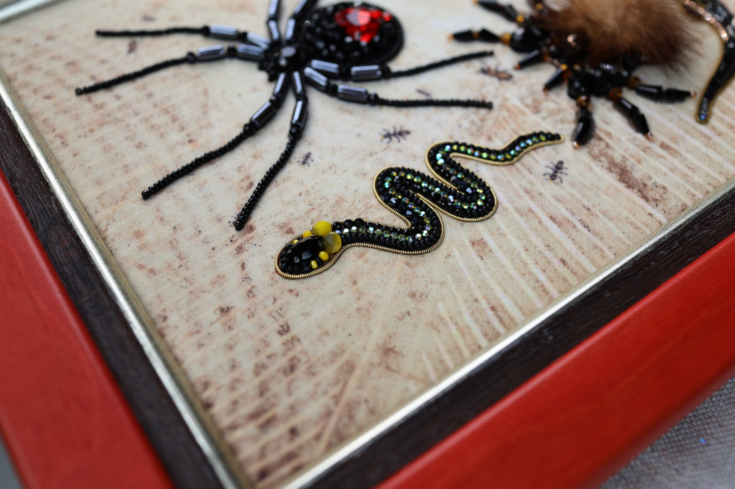 a close-up view of a beaded artwork depicting a spider and a snake.