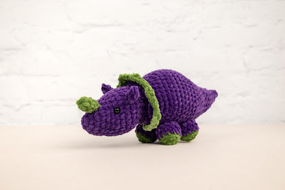 a purple crocheted rhinoceros with a green tail