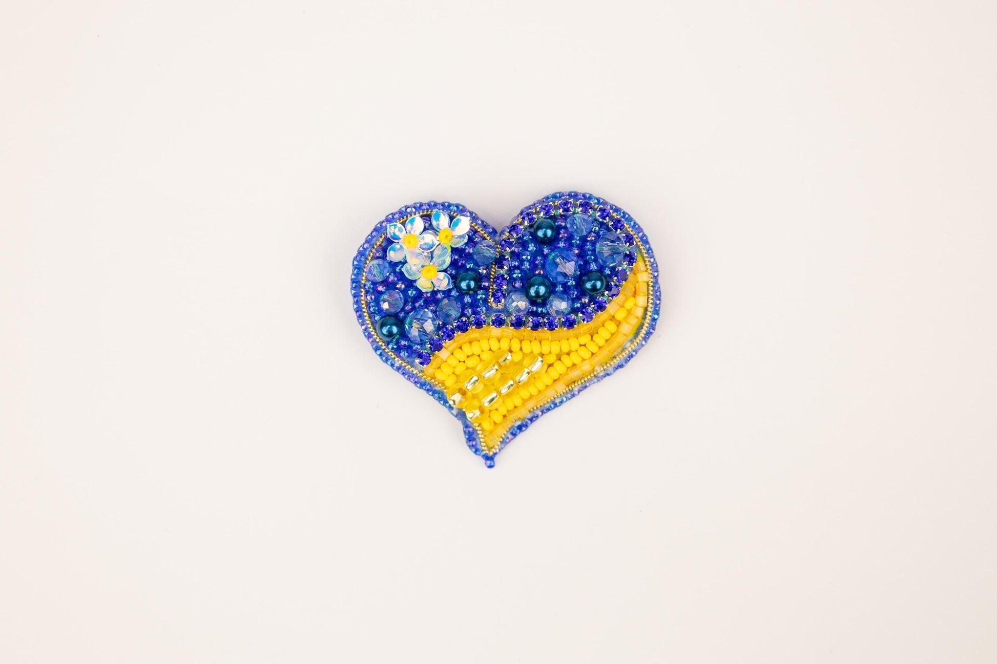 a blue and yellow beaded heart on a white background
