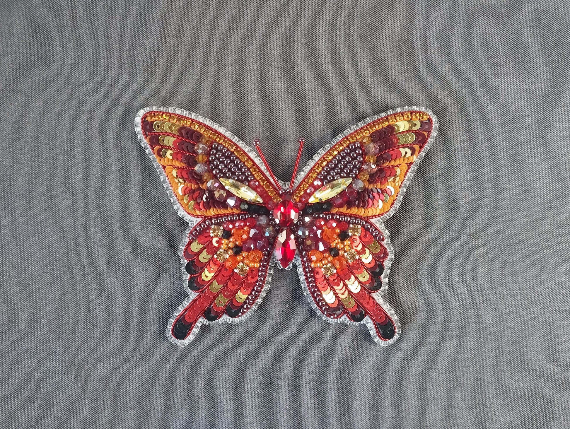 a red and yellow butterfly on a gray surface
