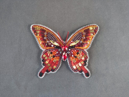 a red and yellow butterfly on a gray surface
