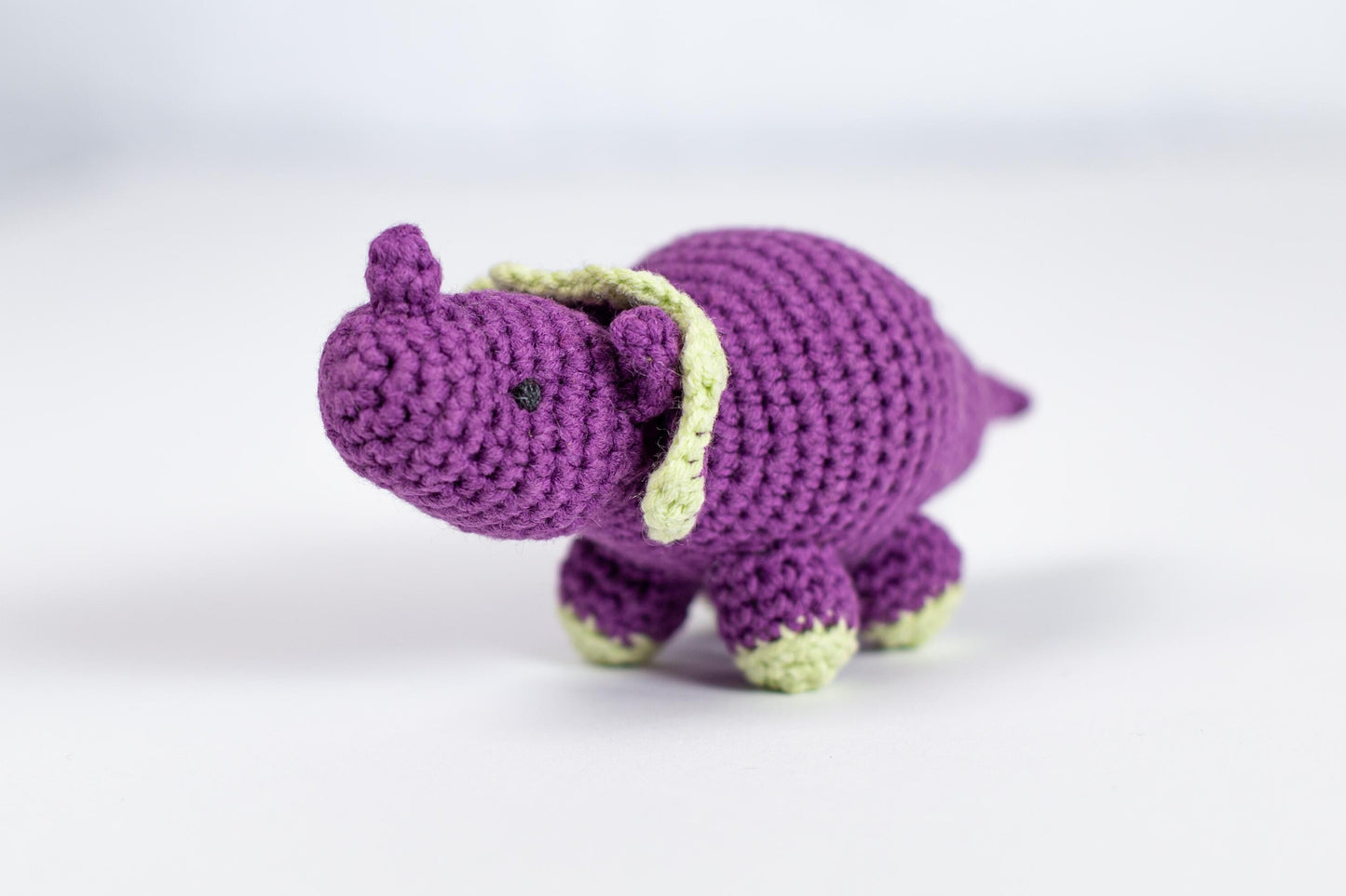 a crocheted purple elephant with a green tail