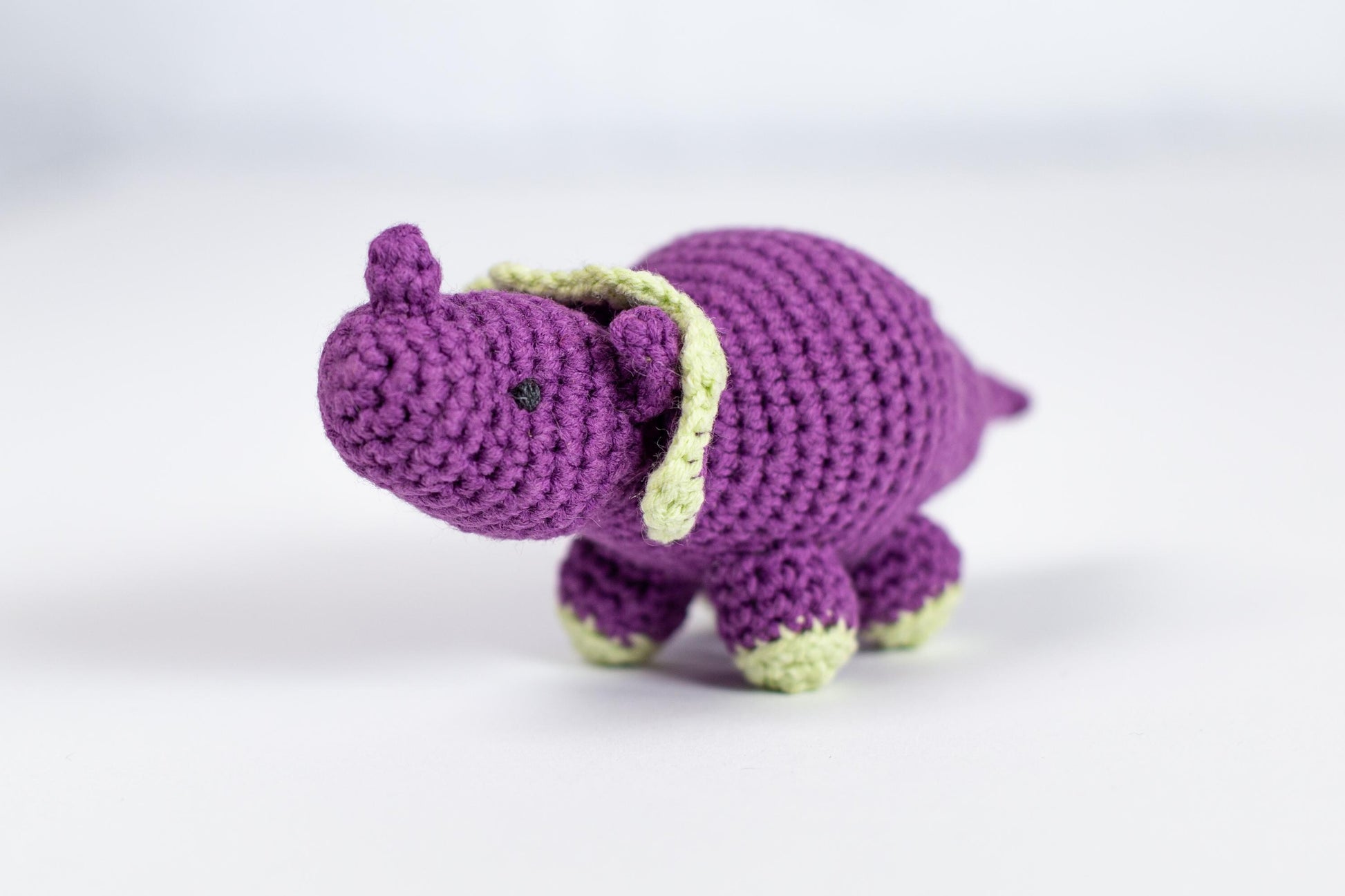 a crocheted purple elephant with a green tail