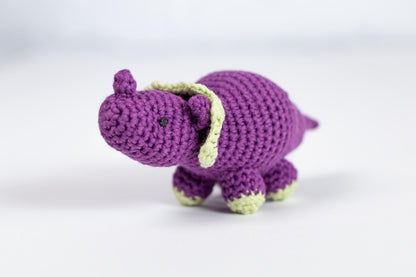 a crocheted purple elephant with a green tail