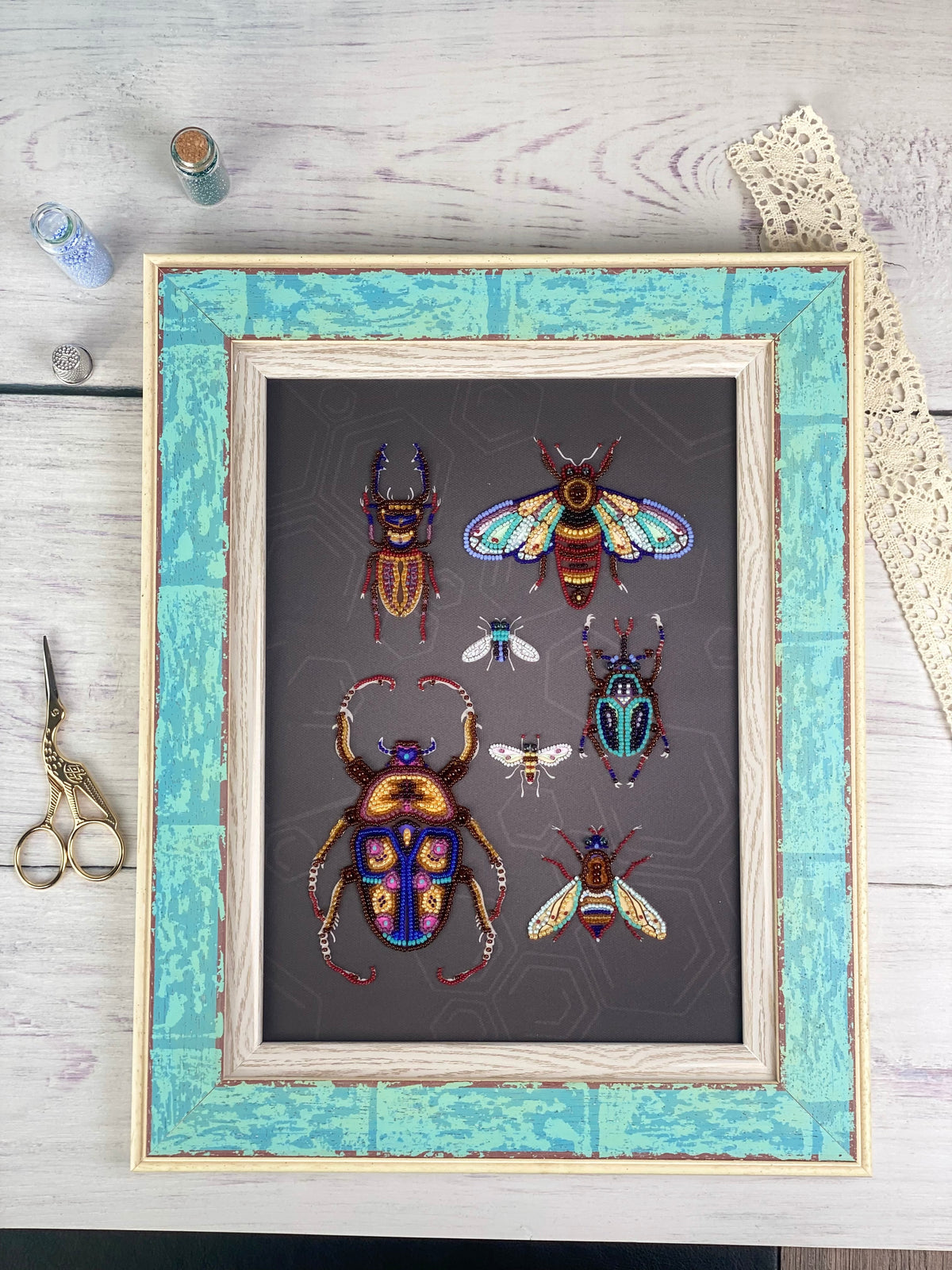 a framed artwork depicting a collection of colorful, detailed insects, including a large dragonfly, a bee, and several other insects, all set against a dark background.