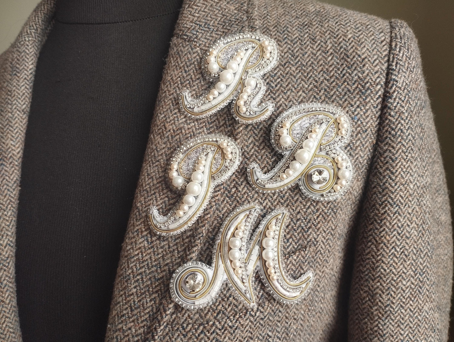 a close-up of a jacket with a decorative embroidered letter on the front.