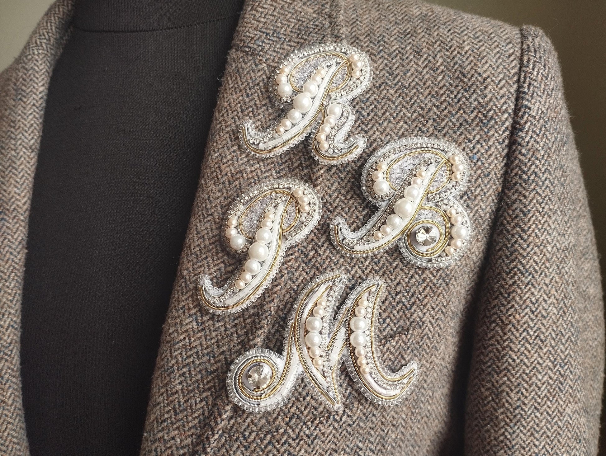 a close-up of a jacket with a decorative embroidered letter on the front.