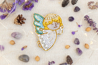 a close-up of a beaded embroidered figure surrounded by various natural elements, including pine cones, gemstones, and purple flowers.