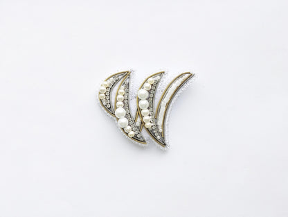 a pair of decorative earrings with a white and gold design, adorned with small pearls and beads.