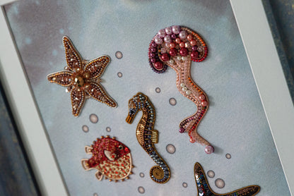 a collection of colorful, intricately designed sea creatures, including a starfish, a jellyfish, a seahorse, a fish, and a pearl.