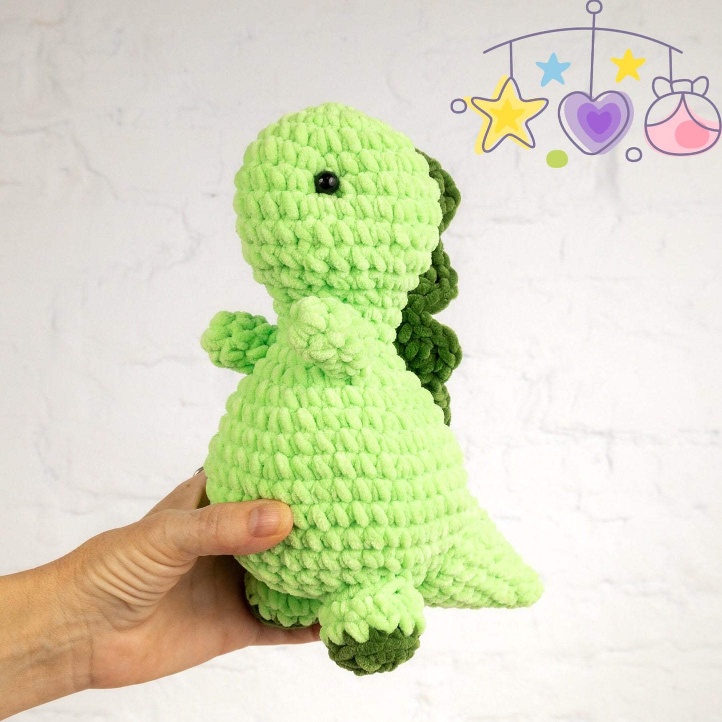 a green crocheted stuffed animal sitting on a table